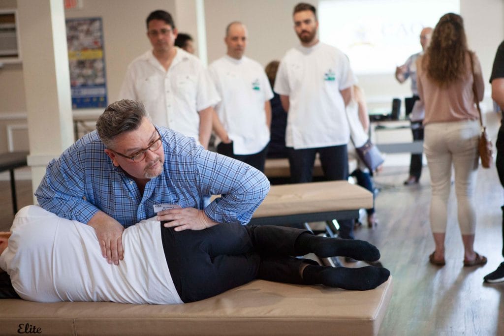 Principal Robert Johnston using osteopathic techniques on a student of the CAO, who is lying on a clinical table